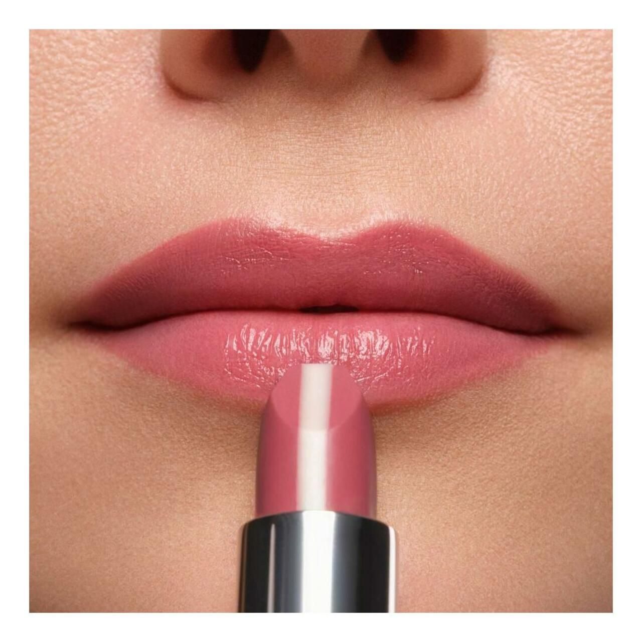 Lippenstift wordt op lippen aangebracht. Roze lippenstift met witte streep. Zilverkleurige houder. Close-up.
