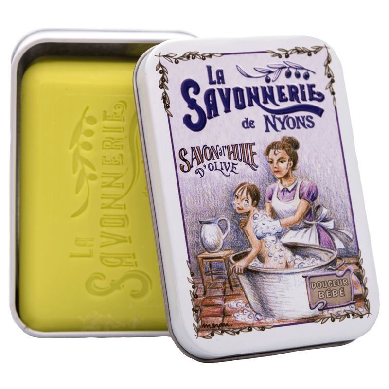 Open metalen doos met zeep. Gele zeep. Tekst: La Savonnerie de Nyons, Savon à l'huile d'olive. Afbeelding van badende vrouw en kind.