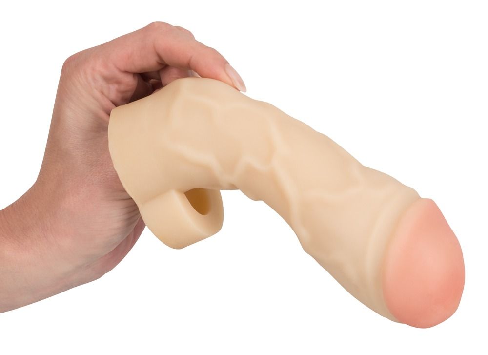 Extension de pénis beige avec extrémité rose, tenue dans une main. Surface texturée.