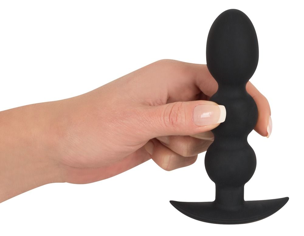 Hand die een zwarte anale plug met drie bollen en brede flens vasthoudt.