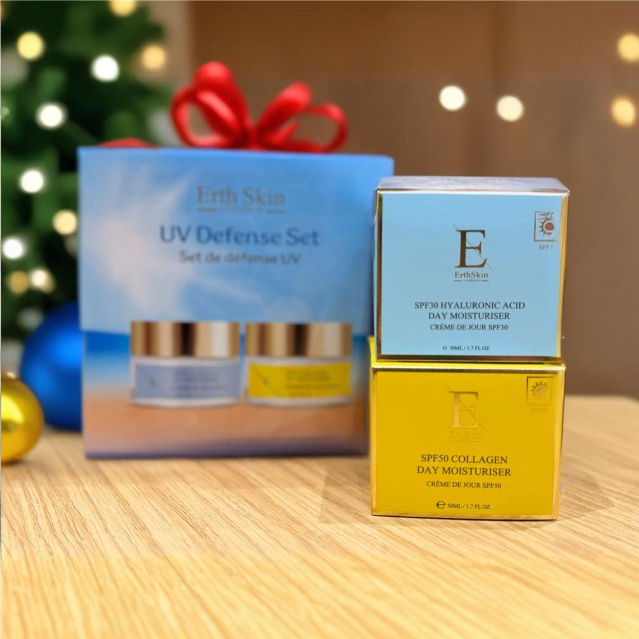 Cadeauset met twee crèmes en twee dozen. "Erth Skin UV Defense Set". Crèmes met gouden deksels en etiketten. Kerstversiering op de achtergrond.