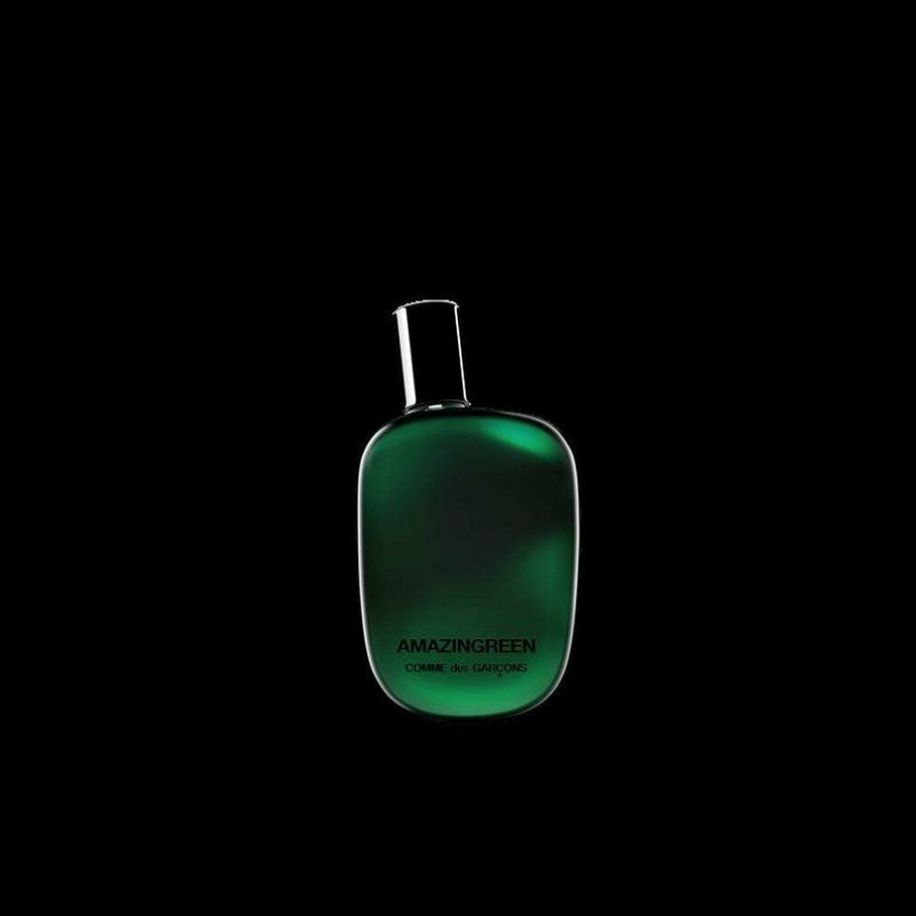 Groene parfumfles met zwarte dop op zwarte achtergrond. Opschrift: AMAZINGREEN, COMME des GARÇONS.