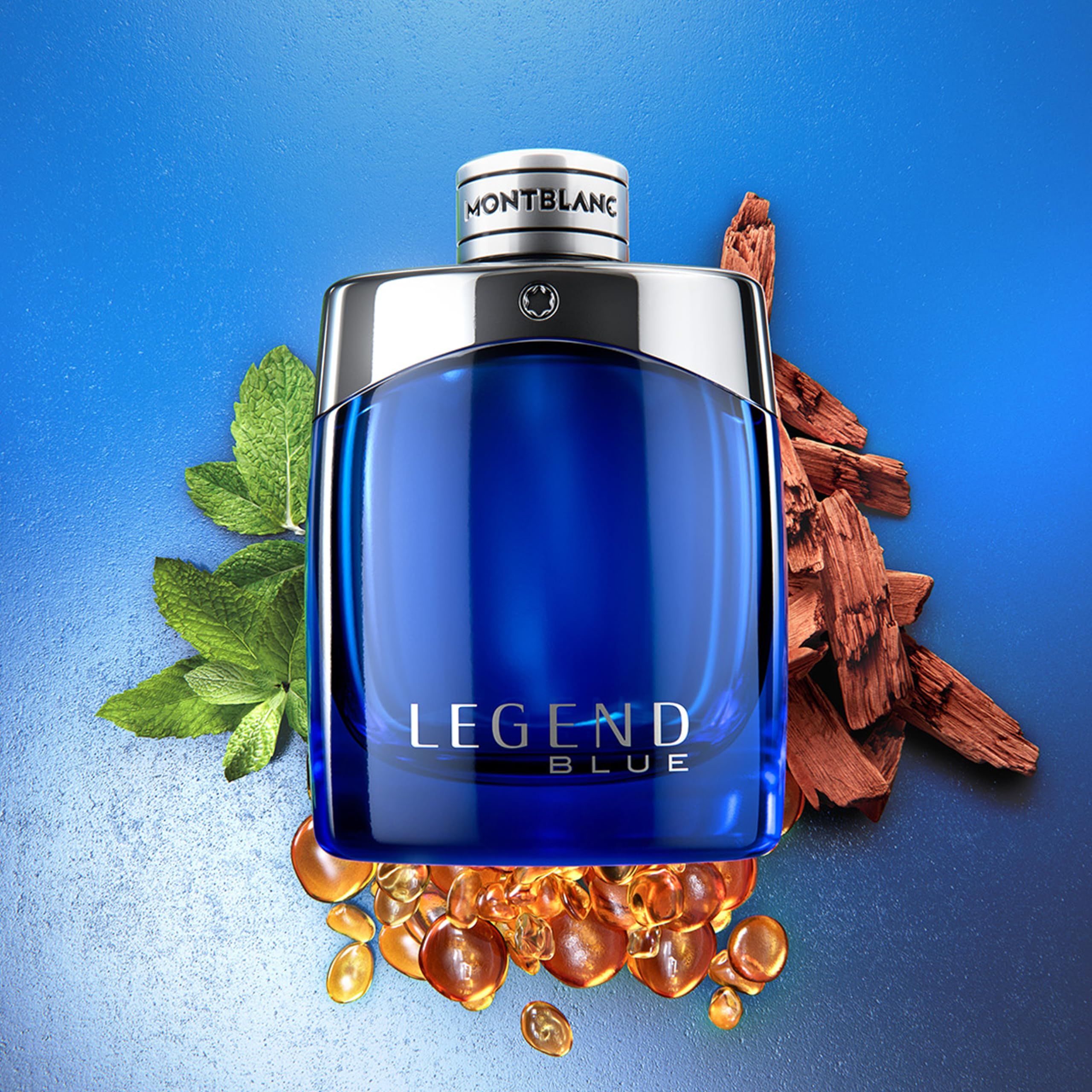 Blauwe Montblanc Legend Blue EdP-fles. Zilveren dop. Decoratie met bladeren en stukjes hout.