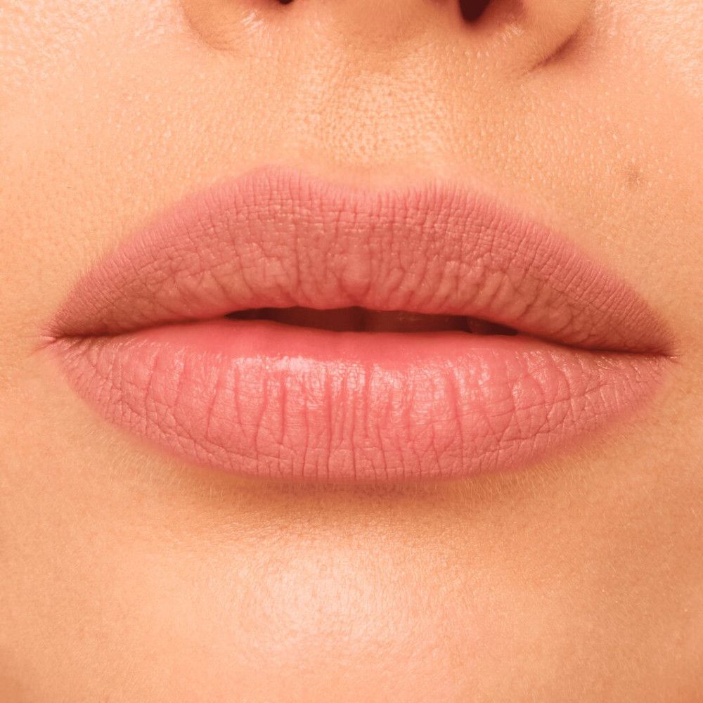 Gros plan sur des lèvres maquillées avec un crayon contour rose. Les lèvres sont légèrement maquillées.