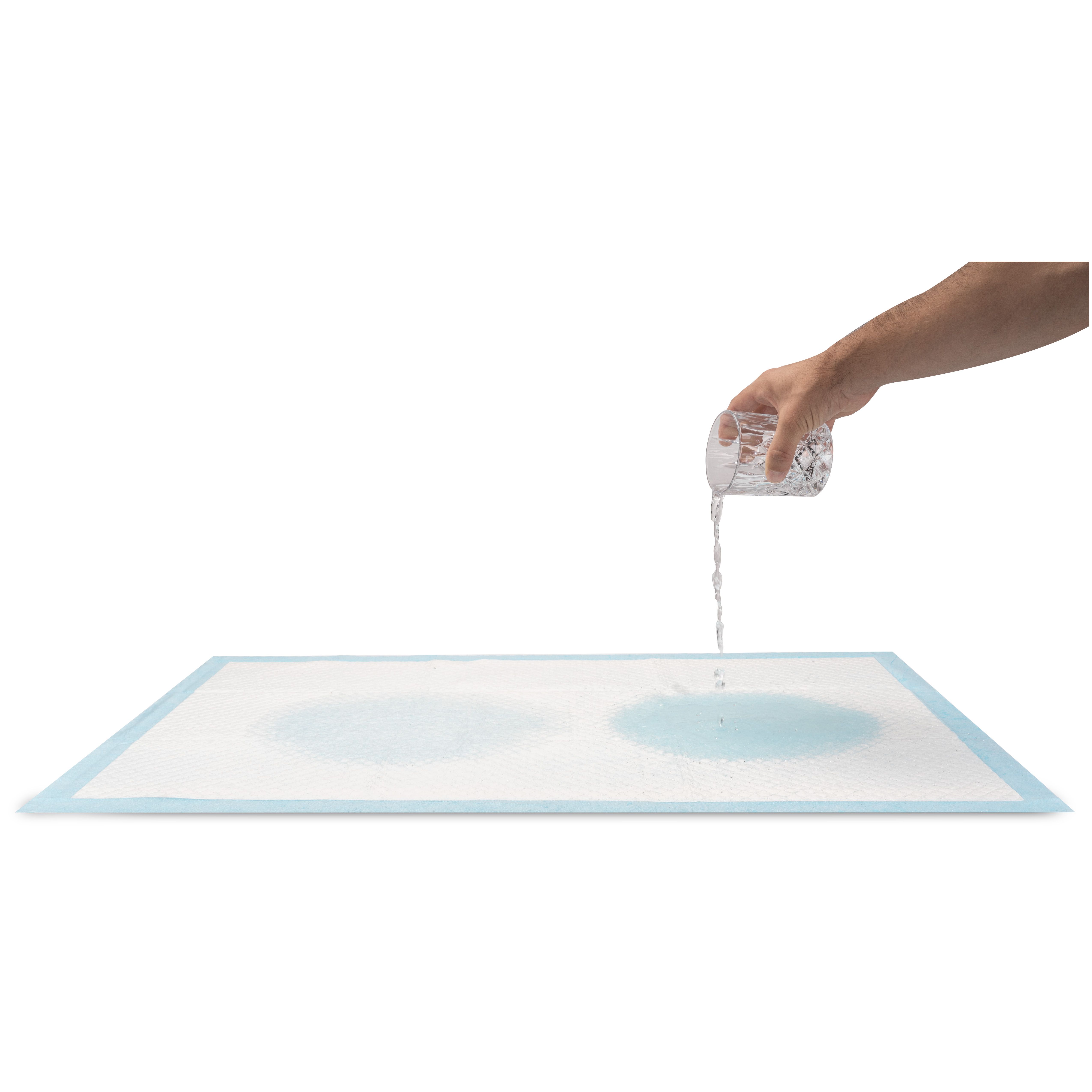 Alèse jetable blanche, de l'eau est versée d'un verre. Deux cercles mouillés sont visibles.