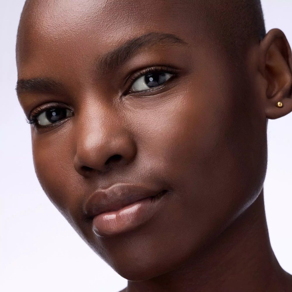 Gros plan d'une femme à la peau foncée. Masque à lèvres. Clou d'oreille doré.