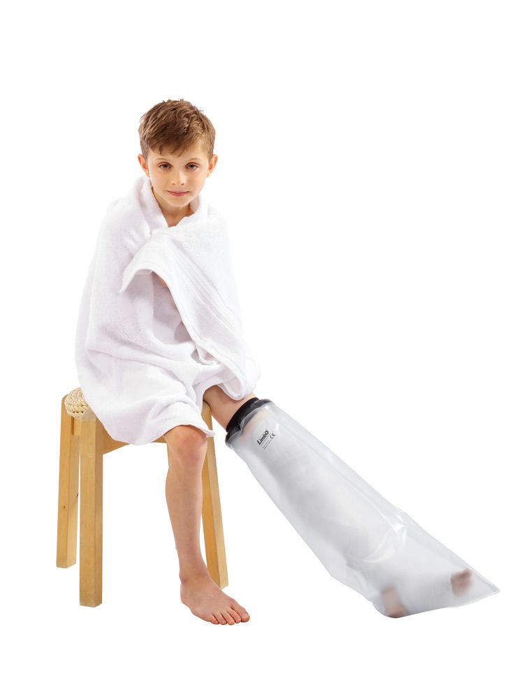 Enfant avec jambe protégée. Protection étanche, embout noir, enveloppe transparente. Assis sur un tabouret, serviette sur les épaules.