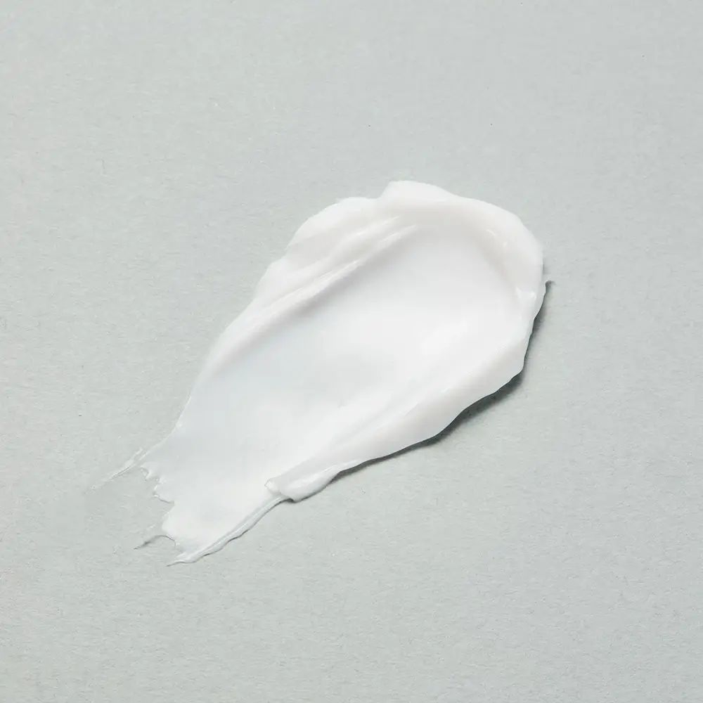 Witte crèmevlek op grijze achtergrond. Textuur zichtbaar.