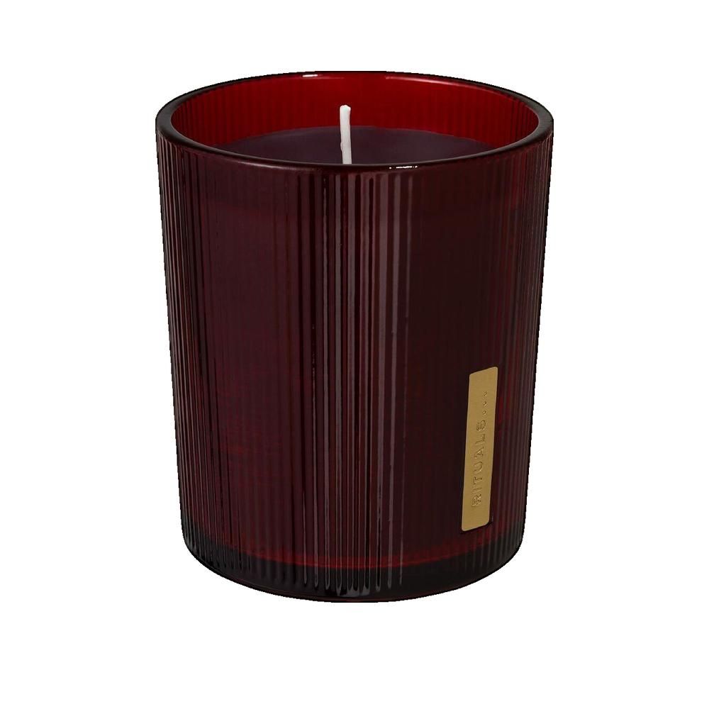 Bougie parfumée rouge dans un récipient en verre cannelé avec une étiquette dorée. Bougie avec mèche.
