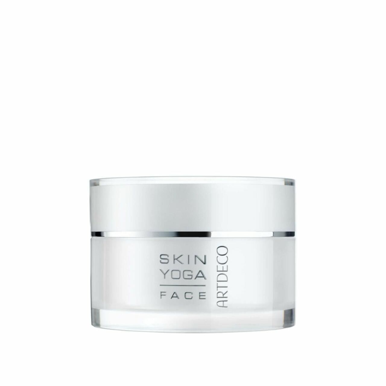 Pot de crème blanc avec couvercle argenté. Texte: Skin Yoga Face, Artdeco. Récipient en verre avec produit.