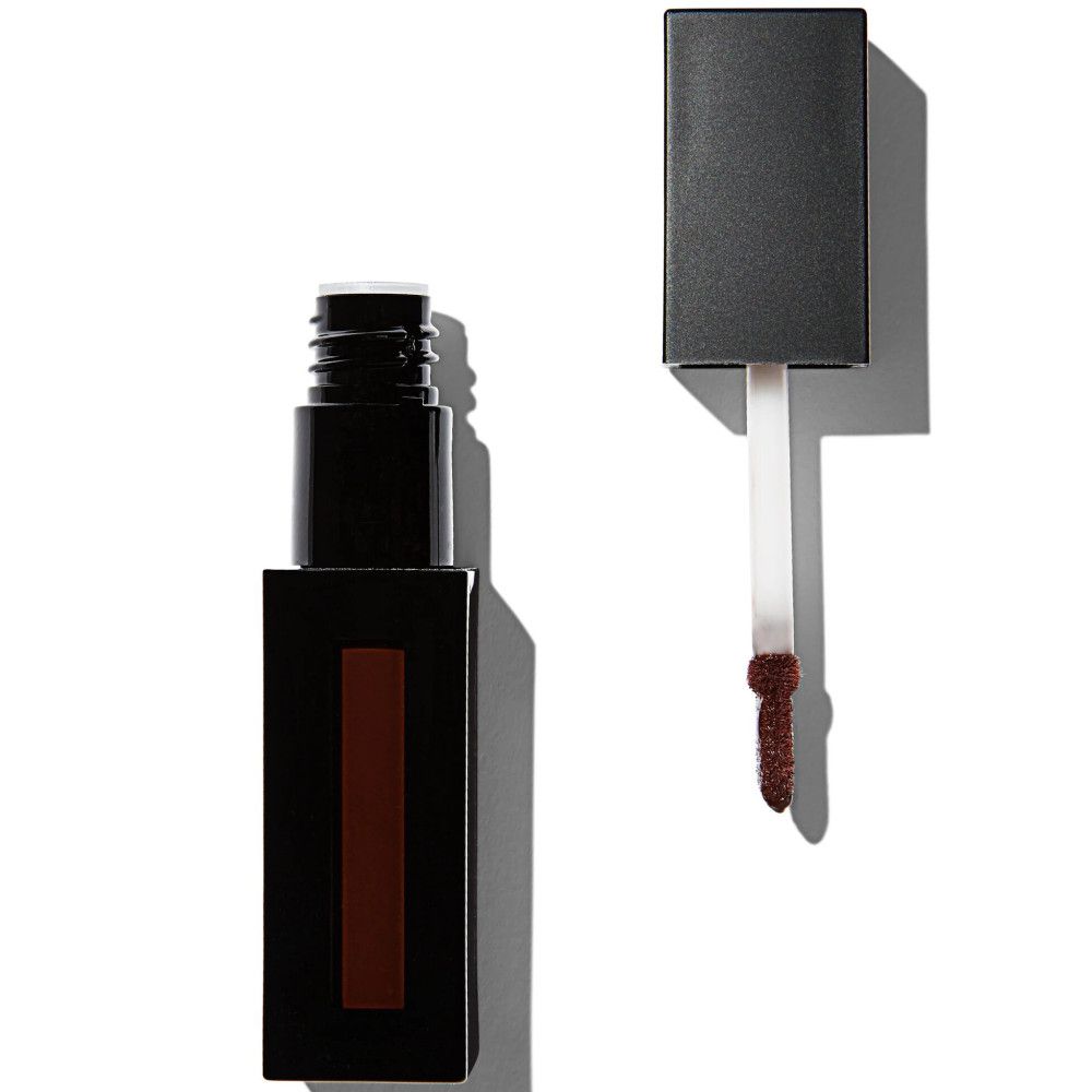 Gloss à lèvres brun foncé en flacon rectangulaire noir. Applicateur visible. Sur fond clair.