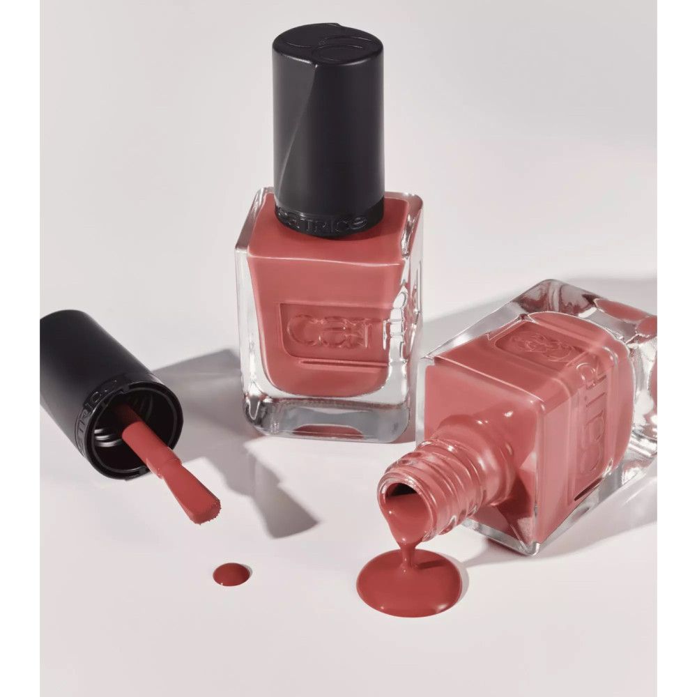 Trois flacons de vernis à ongles rose, marque Catrice. Un flacon couché, le vernis coule. Bouchons noirs.
