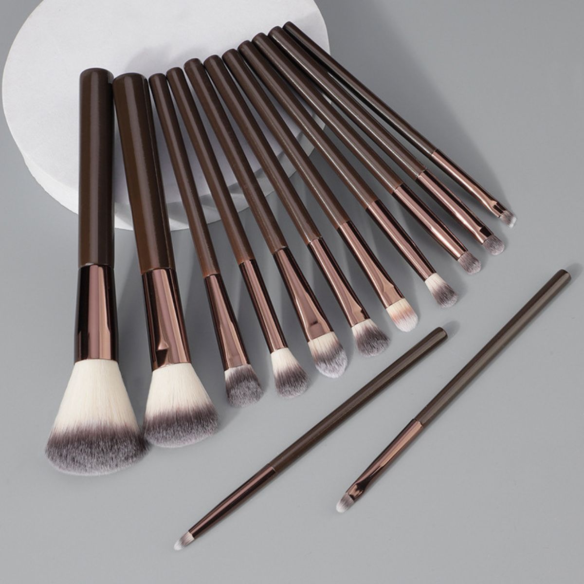 Un ensemble de onze pinceaux de maquillage marron avec des accents métalliques et des poils doux.