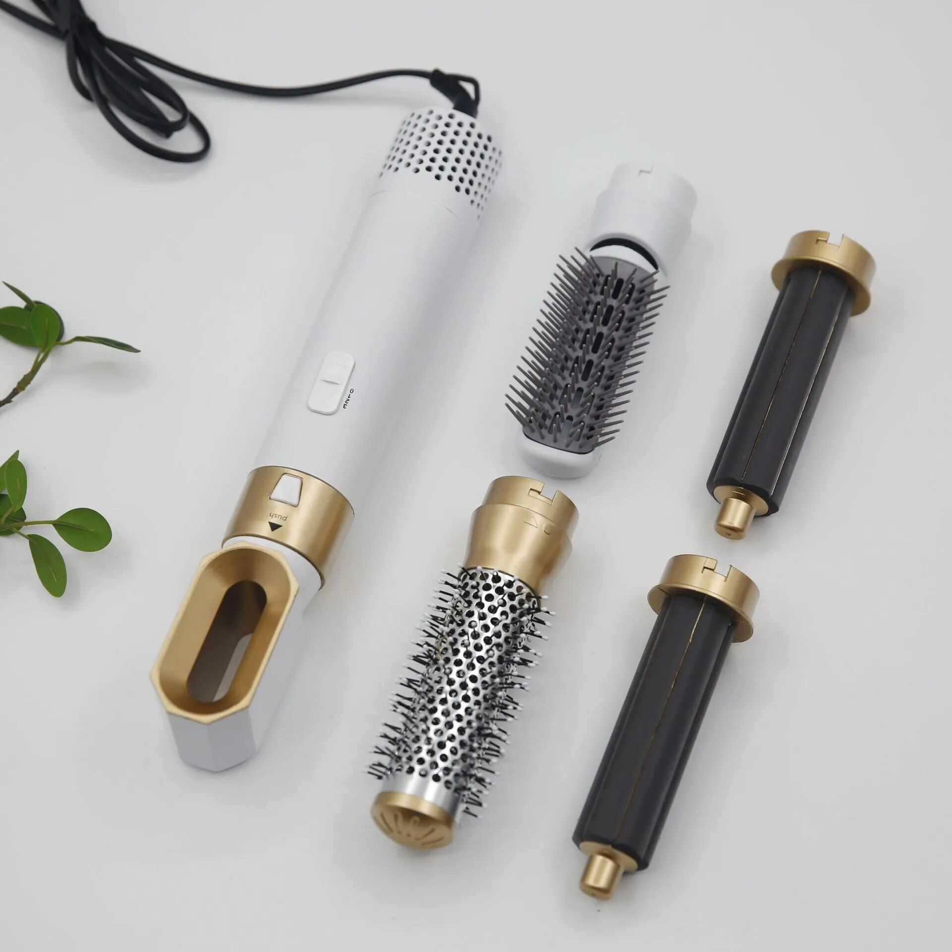 Haarstylingrevolutie met witte handgreep, gouden accenten en diverse opzetstukken. Inclusief borstels en cilinders.
