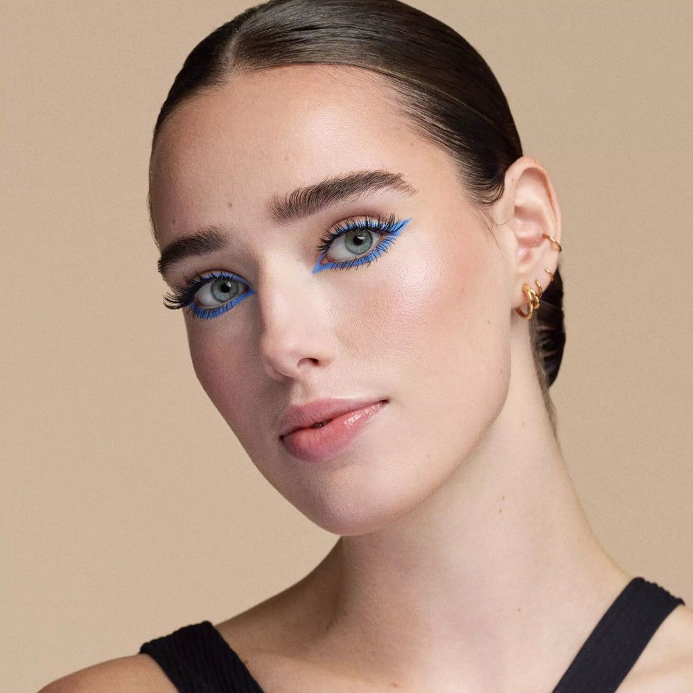 Portrait d'une femme avec un eye-liner bleu et des cils volumineux.