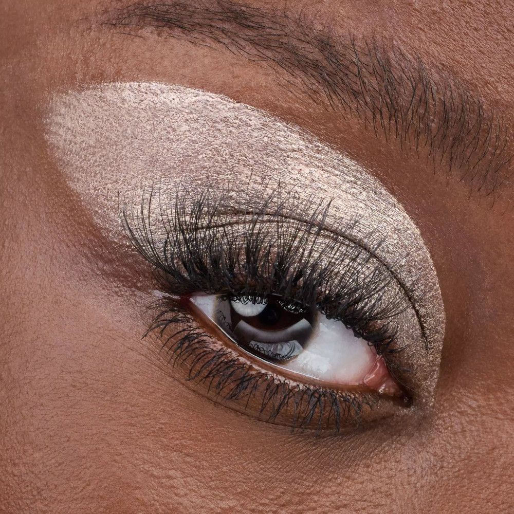 Gros plan sur un œil avec de faux cils appliqués et de l'ombre à paupières. Couleur de peau foncée.