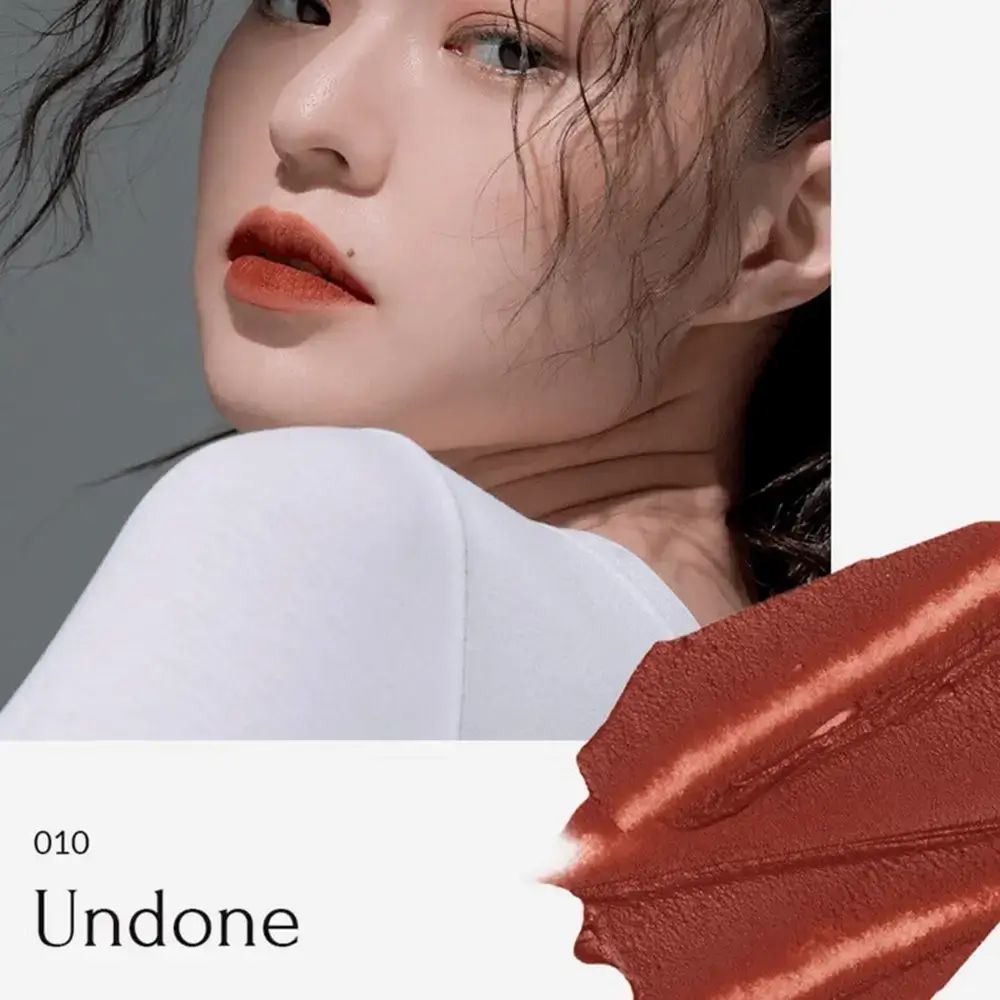 Vrouw met lippenstift. Tint 010 Undone. Lippenstiftveeg. Tekst: Undone, 010. Lichte huid, witte top.