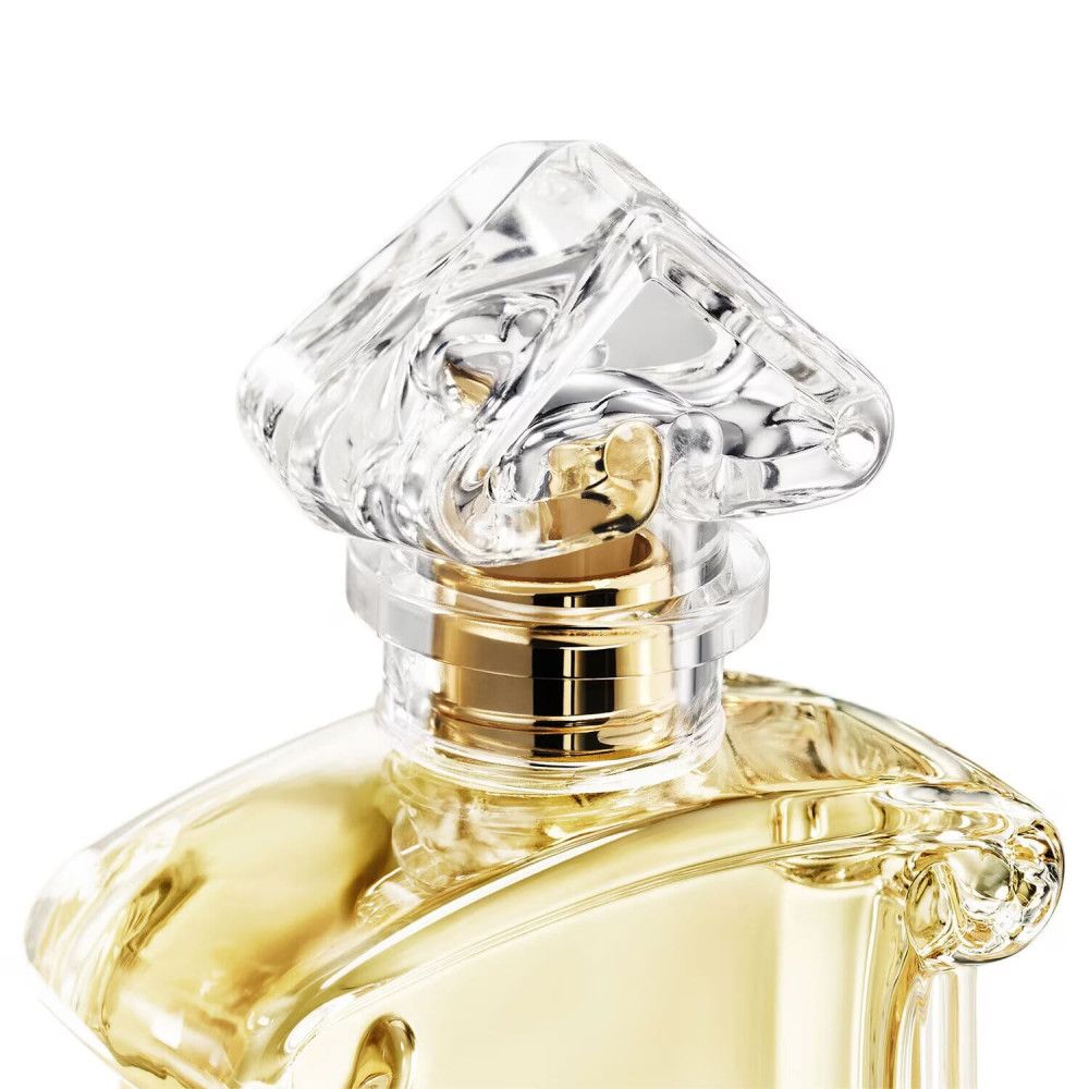 Flacon de parfum avec bouchon transparent. Col doré. Flacon avec liquide jaunâtre.