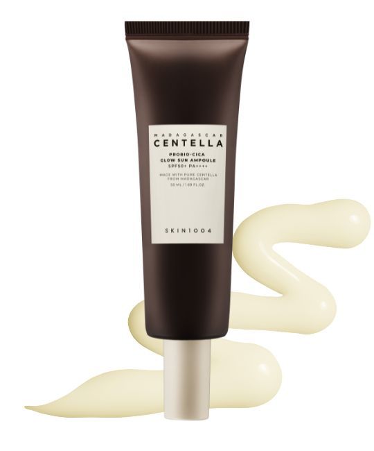 Tube marron avec étiquette blanche. Texte: MADAGASCAR CENTELLA, PROBIO-CICA GLOW SUN AMPULLE SPF50+ PA++++. Trace de produit jaune.