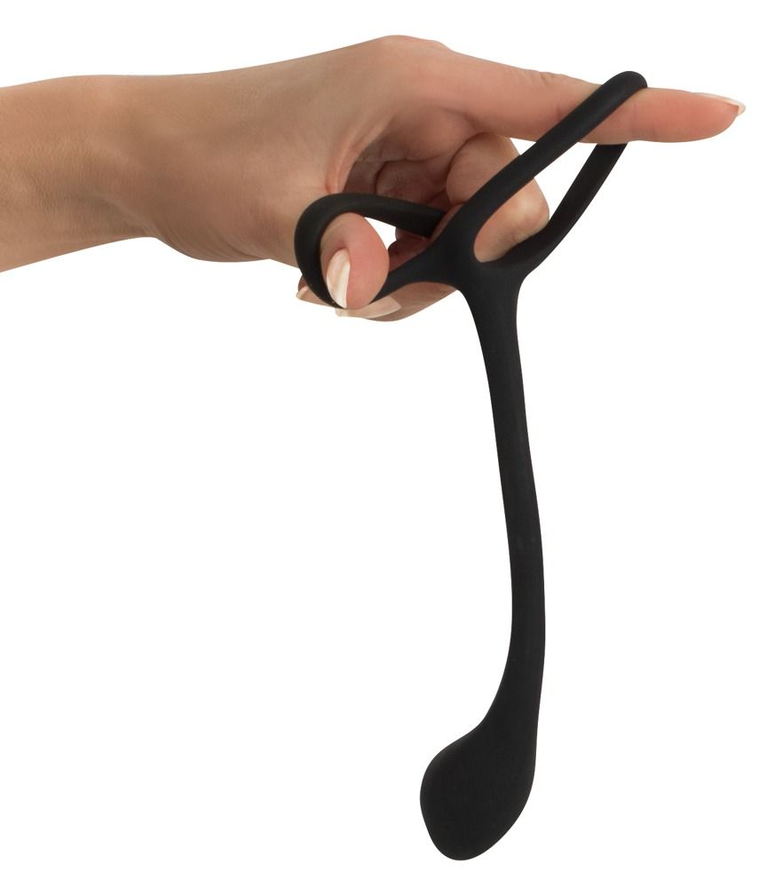Doigt tenant un anneau de pénis/testicules noir avec plug anal en silicone.