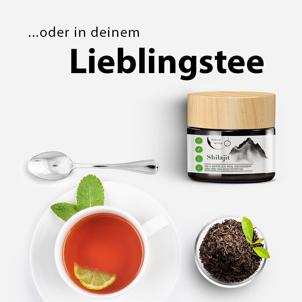 Pot de Shilajit avec couvercle en bois, à côté d'une tasse de thé, citron, feuilles de thé et cuillère. Texte : ...ou dans votre thé préféré.
