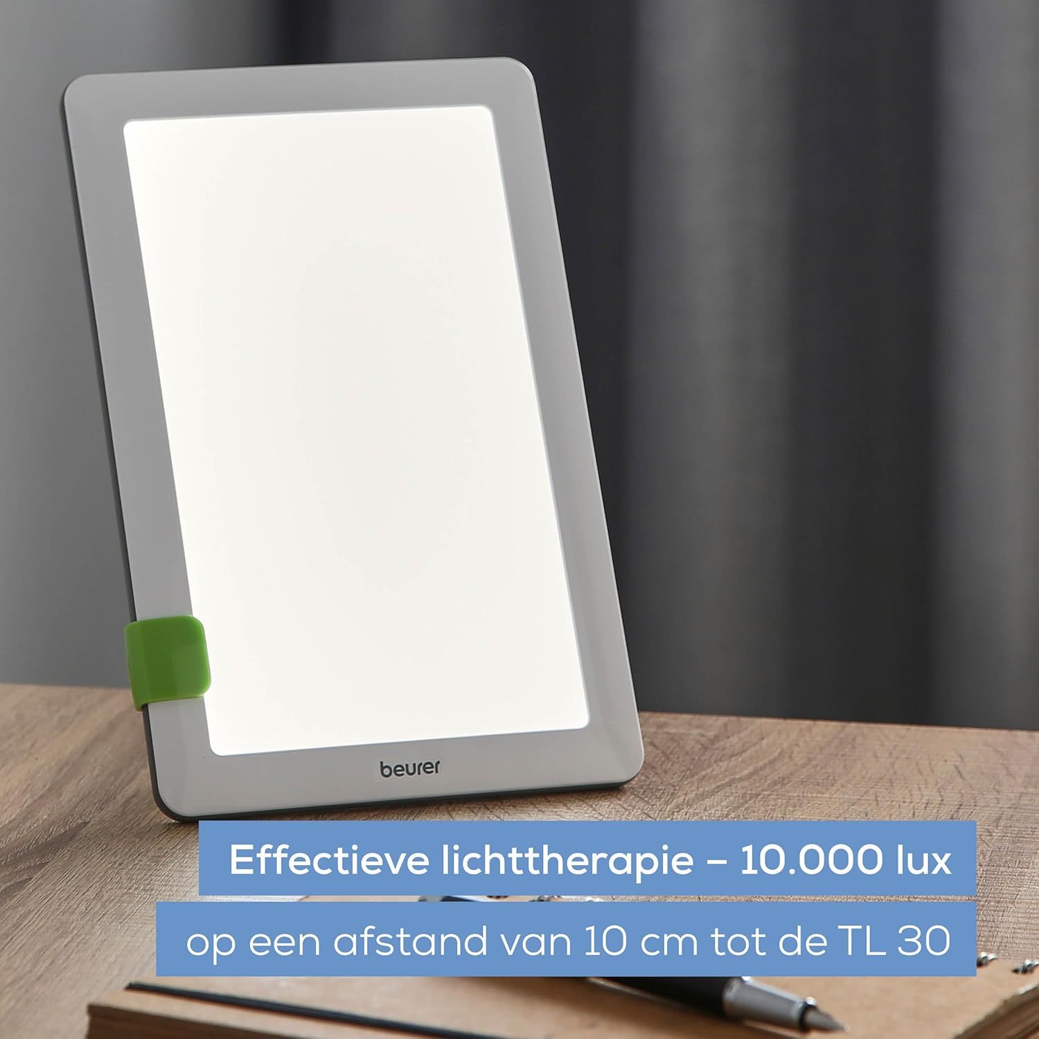 Grijze lichttherapieapparaat met helder verlicht display en groene clip. Merk 'beurer' zichtbaar.