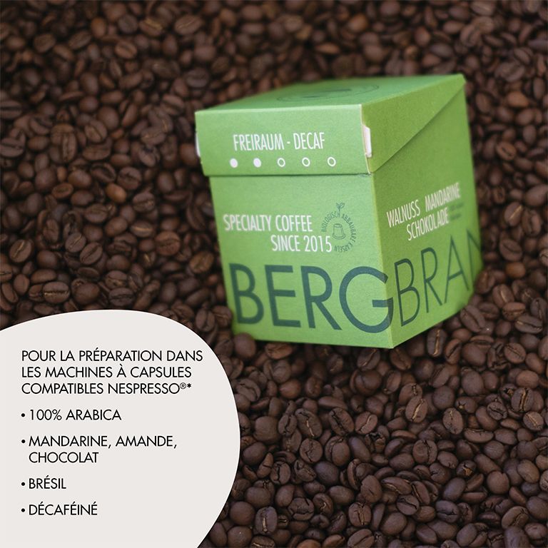 Emballage vert sur grains de café. Texte : BERGBRAND, Freiraum-Decaf, Specialty Coffee. Texte sur le café.
