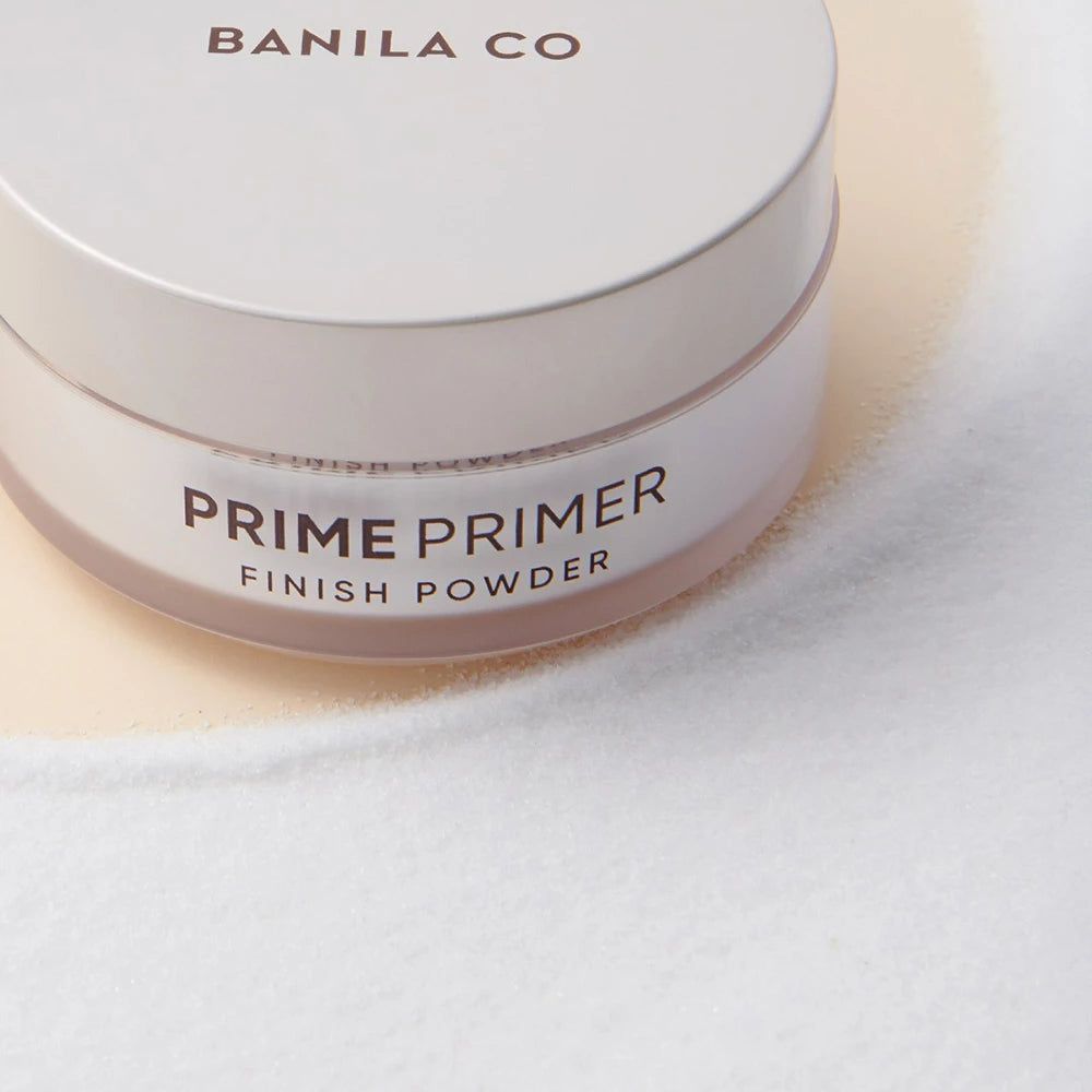 Pot blanc rond avec couvercle. Inscription: BANILA CO, PRIME PRIMER FINISH POWDER. Vue rapprochée.
