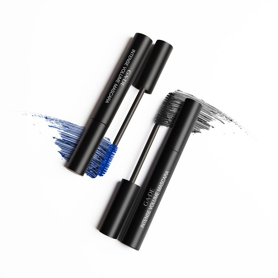 Deux tubes de mascara noirs avec brosses. Inscription: GA-DE Intense Volume Mascara. Taches bleues et noires.