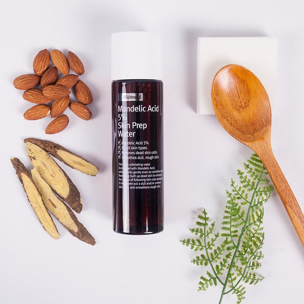 Flacon marron, bouchon blanc, produit à l'acide mandélique. Amandes, morceaux de bois, cuillère, éponge et feuilles sur fond blanc.