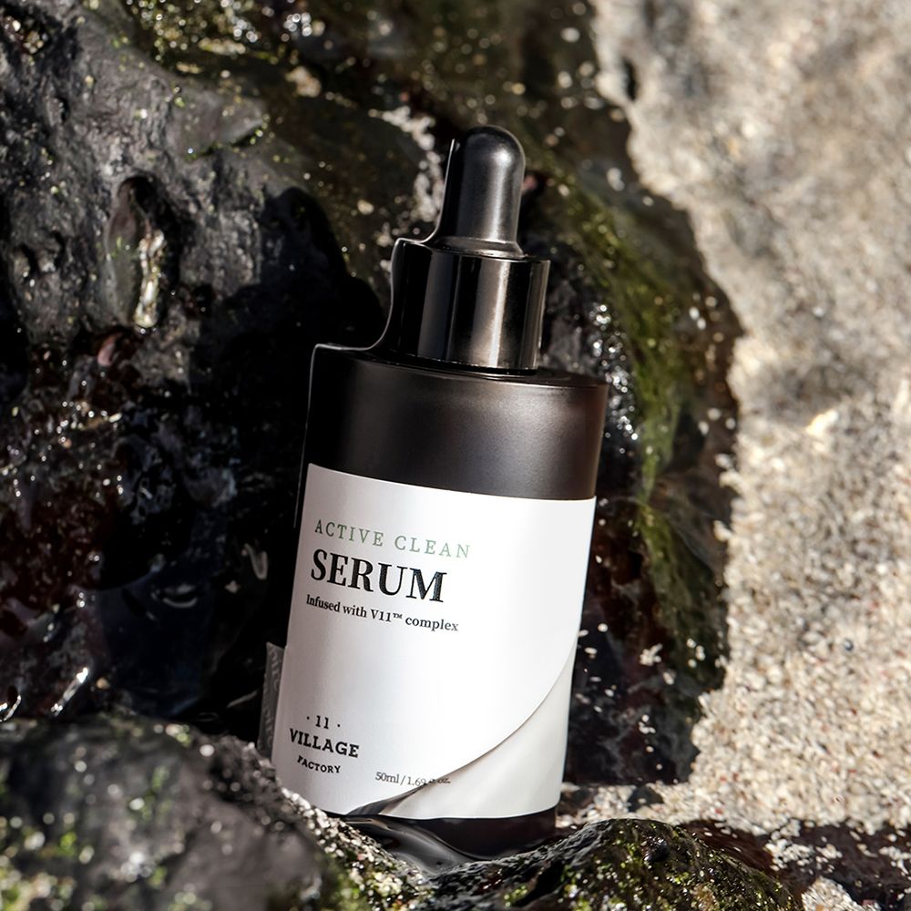 Bruine serumfles met zwarte dop en pipet op rotsen. Wit etiket met "ACTIVE CLEAN SERUM".