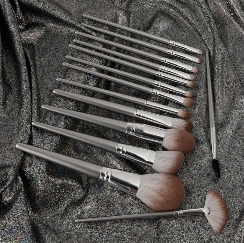 Make-up borstelset op glanzende, zilverkleurige stof. Verschillende borstelvormen met zilveren handvatten.