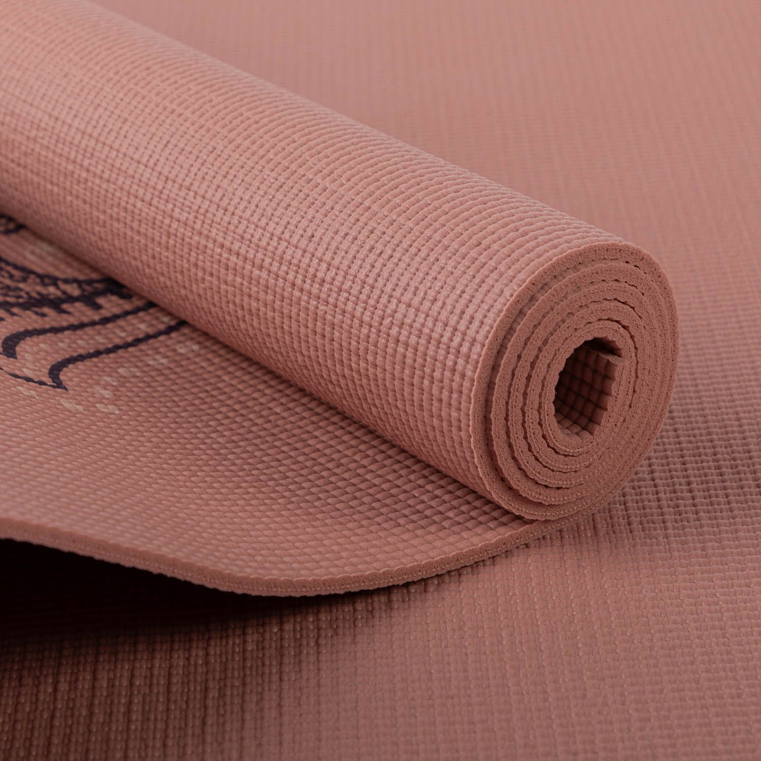 Opgerolde roze yogamat. Hamsa hand design gedeeltelijk zichtbaar. Gestructureerd oppervlak.