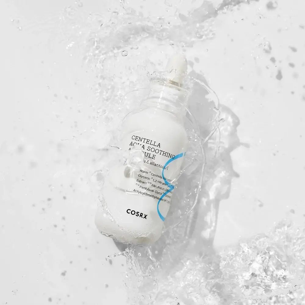 Witte fles met blauw etiket in water. Opschrift: Centella Aqua Soothing Ampoule. Merk: COSRX.