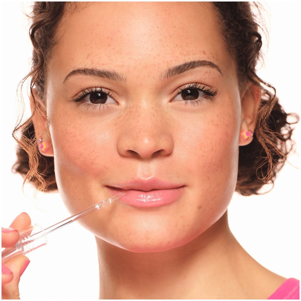 Close-up van een gezicht. Lipgloss aangebracht op de lippen. Lichte huid, sproeten, roze lippenstift.