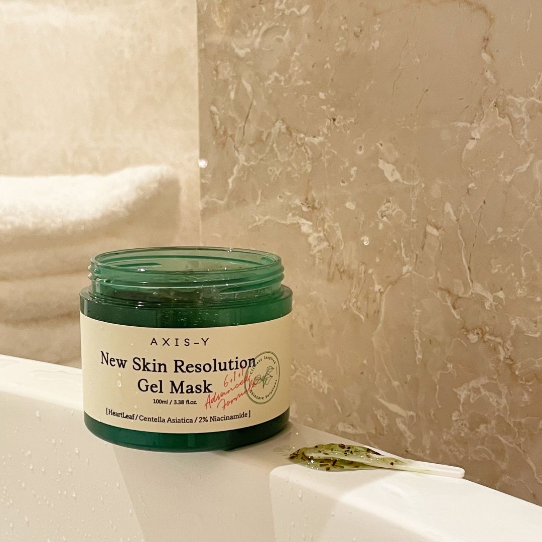 Groene pot AXIS-Y New Skin Resolution Gel Mask. Op een badrand. Spatel ernaast.