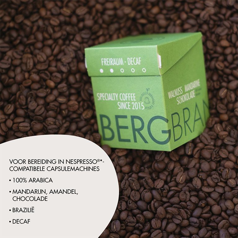 Groene verpakking op koffiebonen. Tekst: BERGBRAND, Freiraum-Decaf, Specialty Coffee. Tekst over koffie.