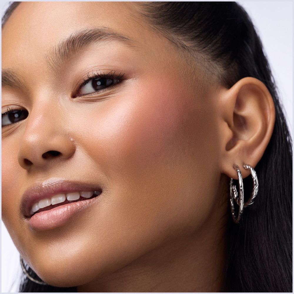 Gros plan sur une femme avec du fard à joues sur la joue. Aucun emballage de produit visible.