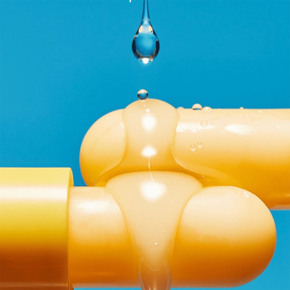 Close-up van gele lippenbalsem-sticks met druppels. Vloeistof op de sticks, blauwe achtergrond.