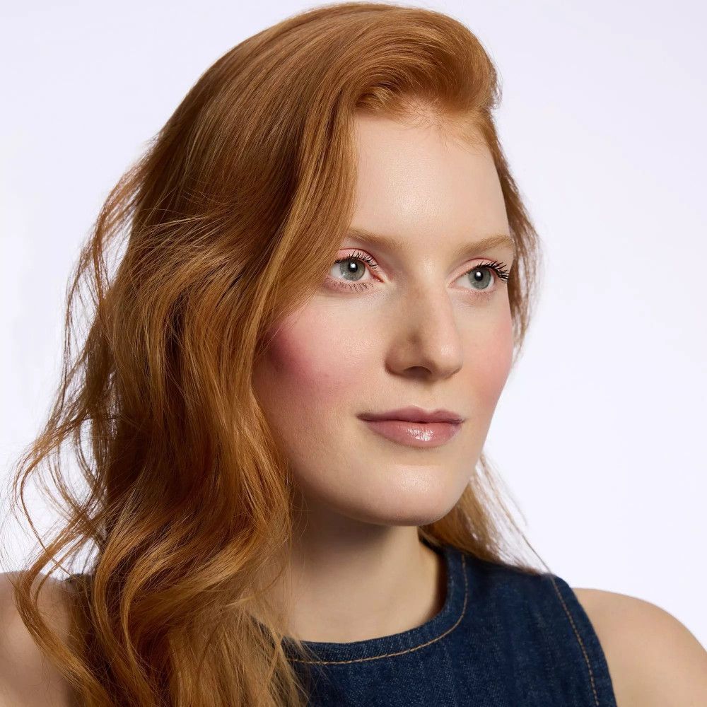 Portret van een vrouw met rood haar. Ze draagt lipgloss. Lichte huidskleur.