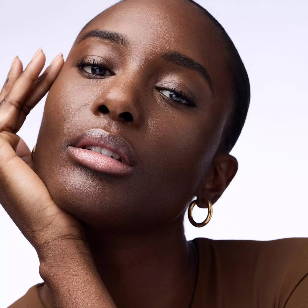 Portret van een vrouw met een donkere huid en donker haar. Ze draagt gouden oorbellen.