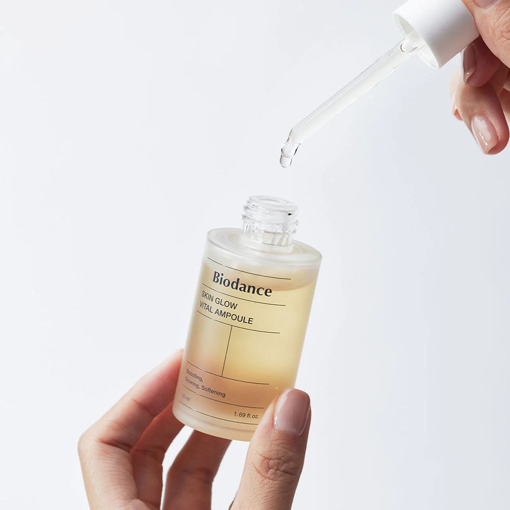 Mains tenant flacon de sérum et pipette. Gouttes tombent de la pipette.