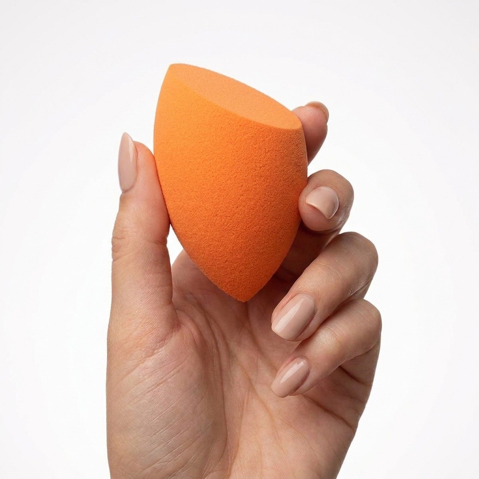 Éponge de maquillage orange à pointe biseautée, tenue dans une main.