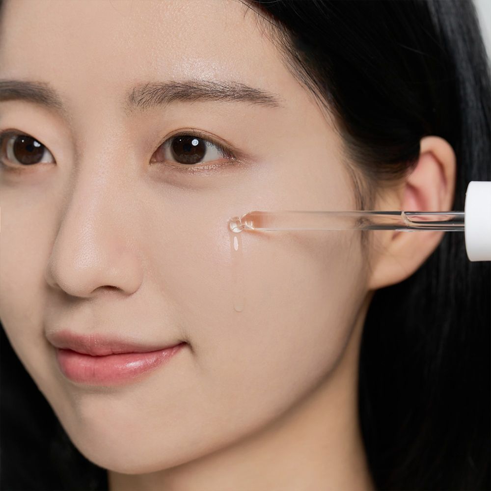 Gros plan d'un visage recevant une goutte de liquide d'une pipette.