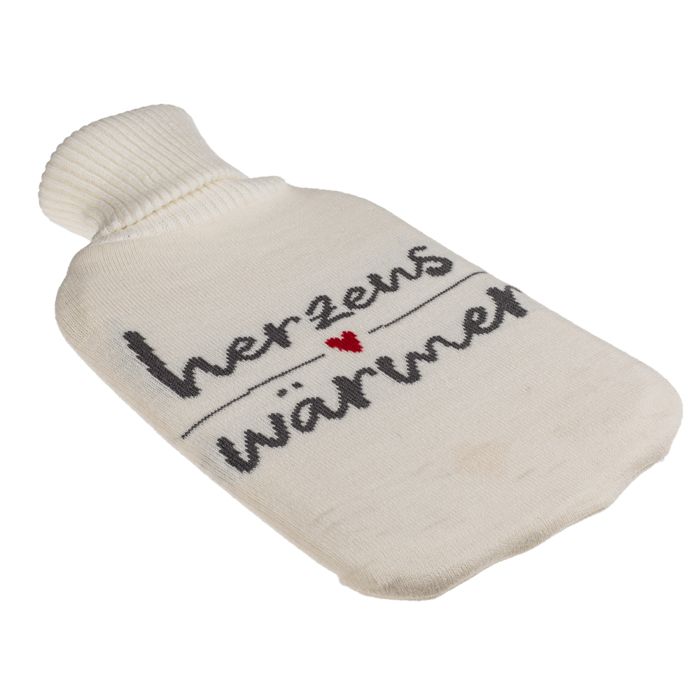 Crèmekleurige warmwaterkruik met gebreide hoes. Opschrift 'Herzenswärmer' in zwart met rood hart. Schuin aanzicht.