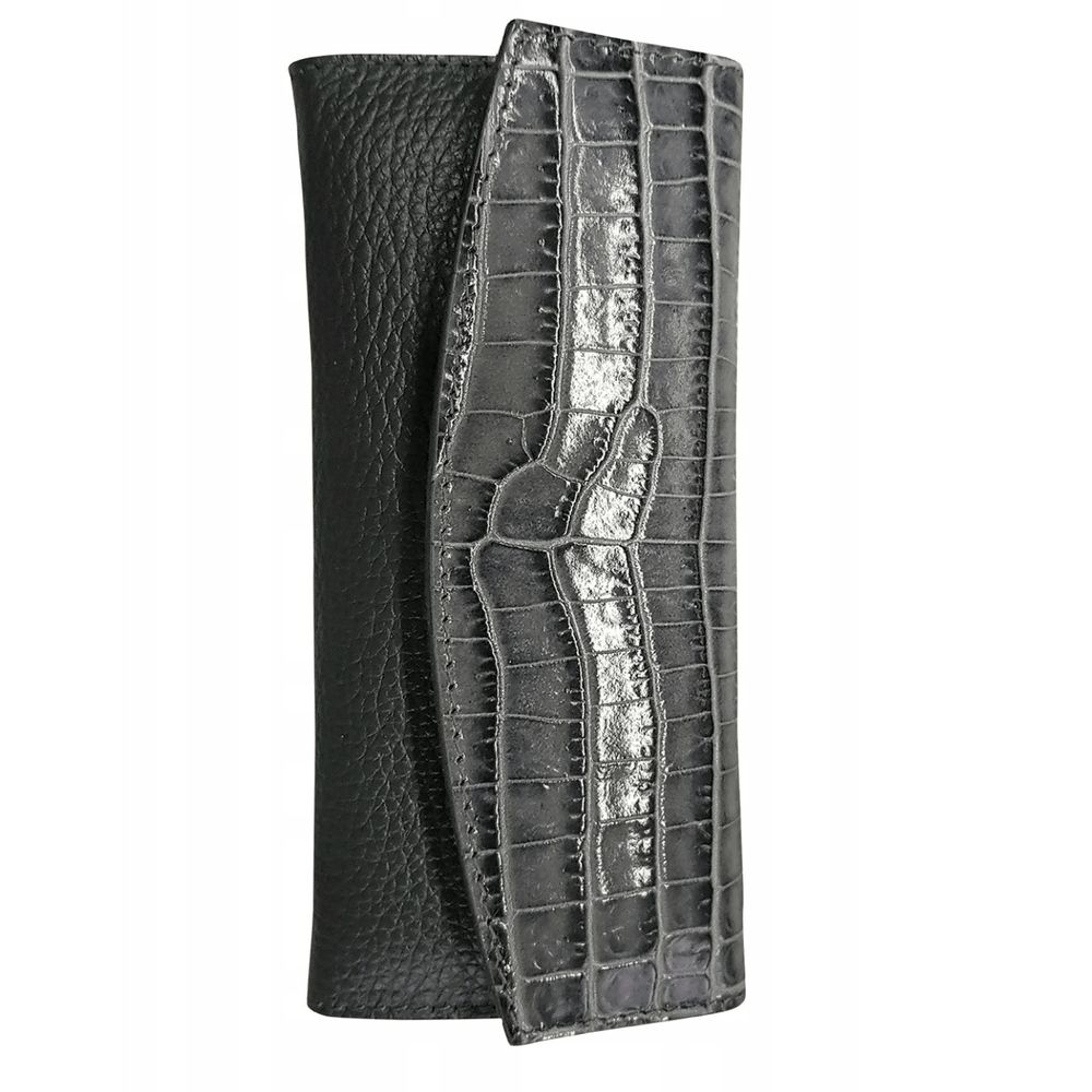 Étui gris aspect crocodile partiellement ouvert. Cuir noir visible. Forme rectangulaire avec rabat.