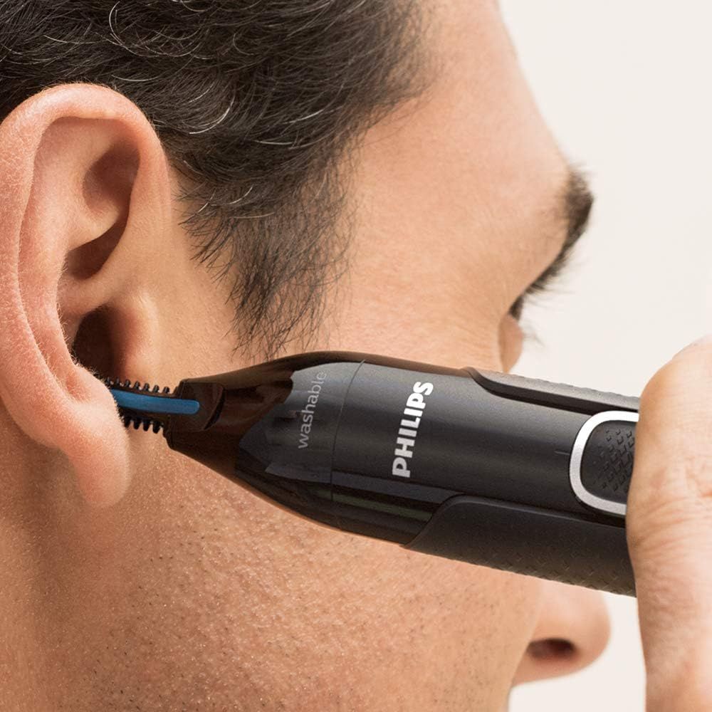 Man trimt oren met Philips trimmer. Zwart apparaat, blauw trimdeel.