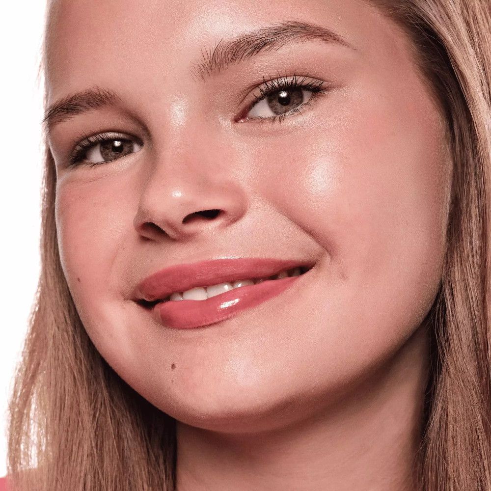 Portret van een vrouw met roze lipgloss. Ze glimlacht. Huid en lippen glanzen.