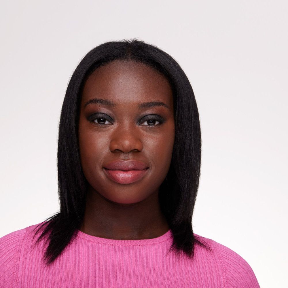 Portret van een donkere vrouw met oogschaduw. Ze draagt een roze top.