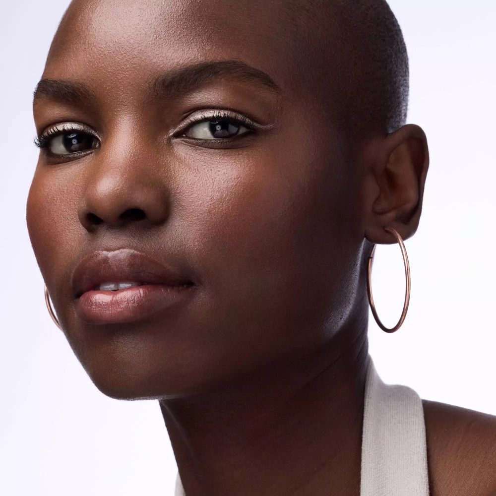 Portrait d'une femme avec un eye-liner brun clair. Elle porte des créoles dorées.